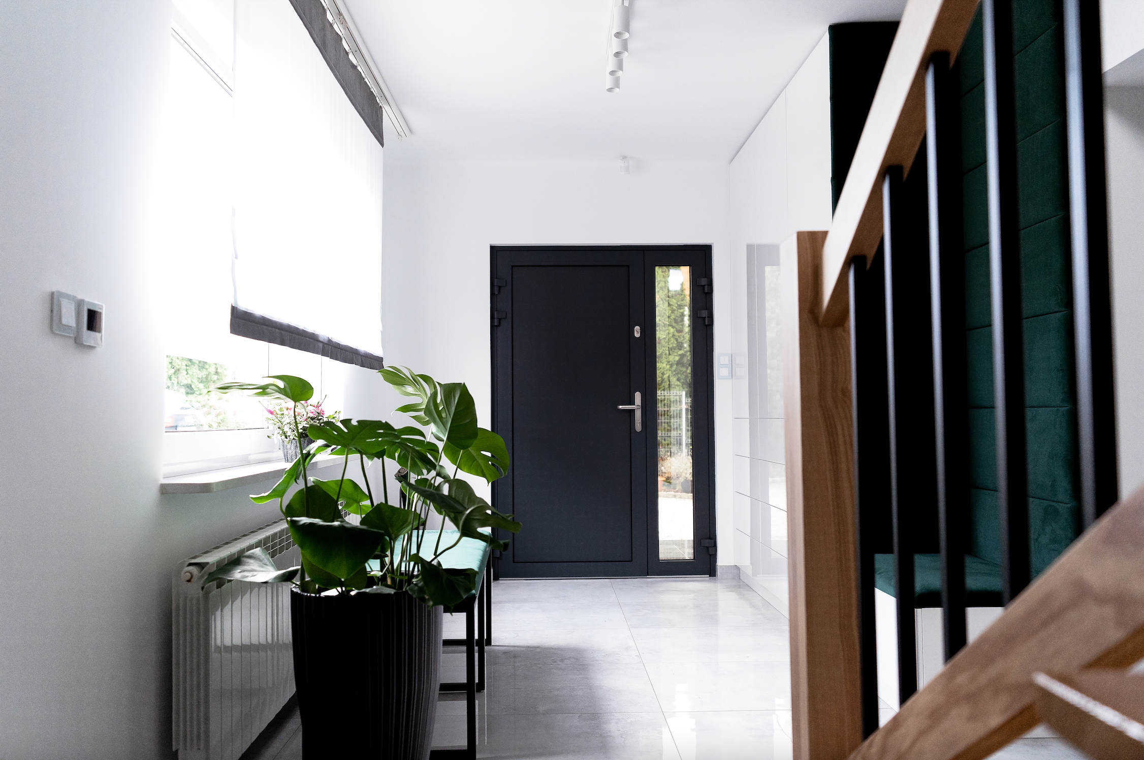 A minimalist white entryway looking onto a black aluminum exterior door.