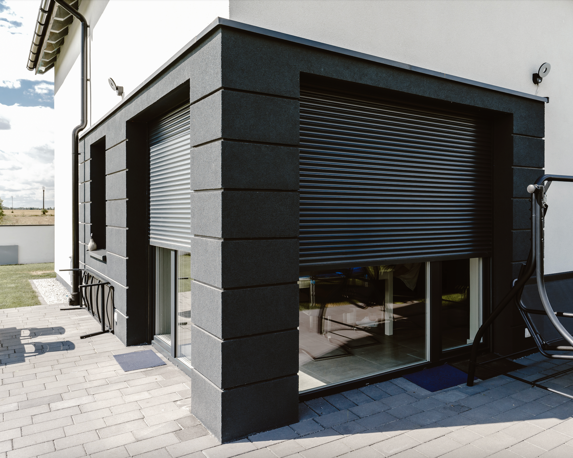 Modern black exterior roller shutters on a residential building patio.