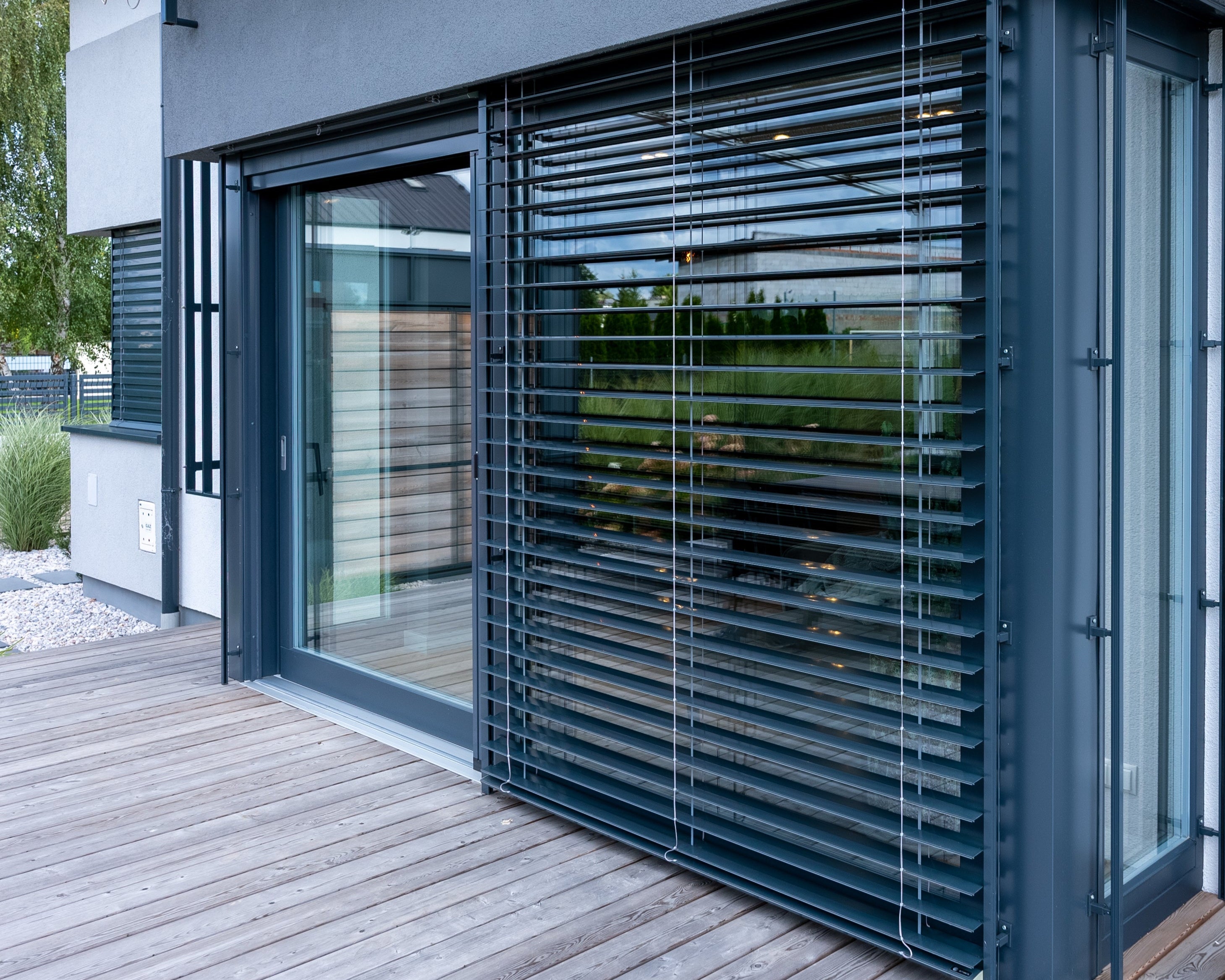 Modern house patio exterior with black exterior venetian blinds over a patio door.